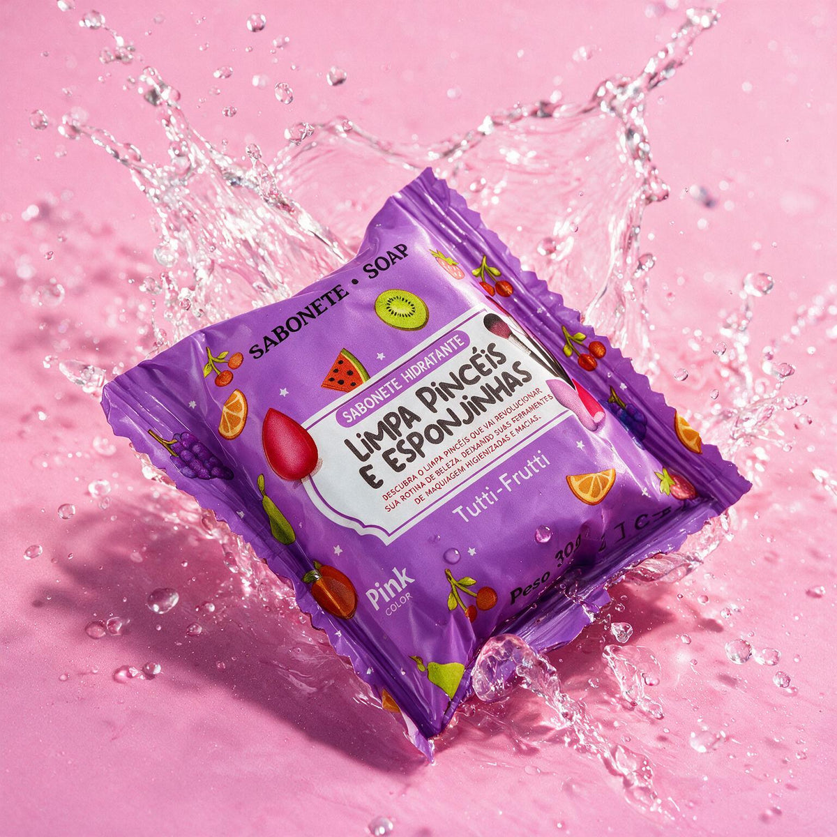Sabonete limpa pincéis Tutti-Frutti com respingos de água em fundo rosa